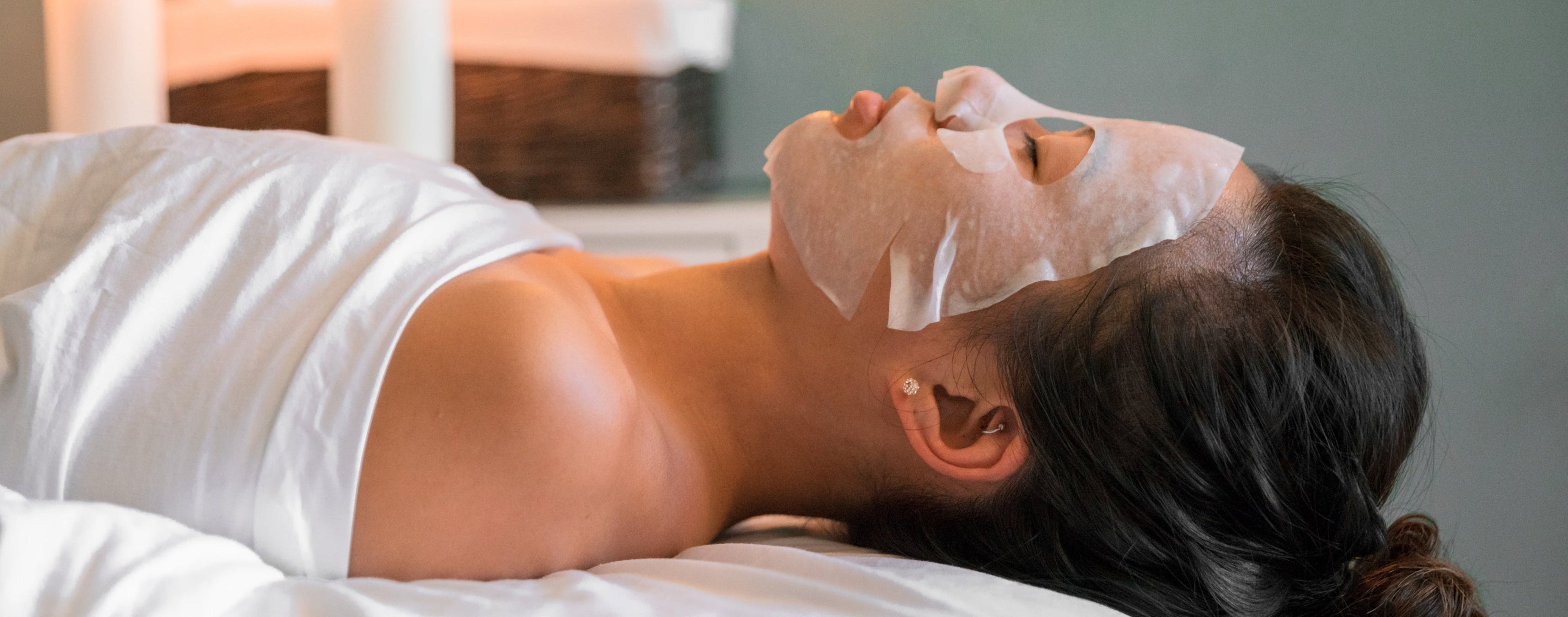 Woman getting a facial with a sheet Mask at Radiant Skin and Body